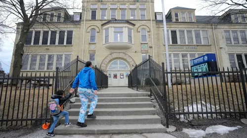 امرأة وطفل يسيران نحو مدخل مدرسة قديمة في ميلووكي، حيث تم الإعلان عن إغلاق مؤقت للمدارس بسبب أزمة الرصاص.