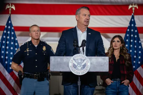 تود ليونز، القائم بأعمال مدير إدارة إنفاذ قوانين الهجرة والجمارك، يتحدث خلال مؤتمر صحفي، مع خلفية علم أمريكي.