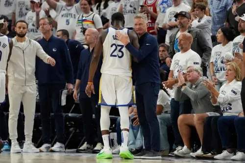 مدرب فريق غولدن ستيت ووريورز يتحدث مع أحد لاعبيه بعد المباراة، حيث يظهر جمهور متحمس يرتدي قمصان الفريق.