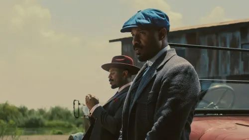 مشهد من فيلم "المذنبون" يظهر شخصيتين رئيسيتين ترتديان ملابس أنيقة، مع سيارة قديمة في الخلفية، مما يعكس أجواء ثلاثينيات القرن العشرين في ميسيسيبي.