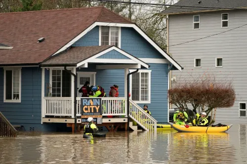 مشهد لفرق الإنقاذ في قوارب كاياك أثناء عمليات الإجلاء من منزل غمرته الفيضانات في واشنطن، مع ارتفاع المياه حول المباني.