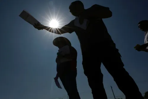 أشخاص يقفون في ضوء الشمس، يحملون أوراقًا، في سياق مناقشة حول الانتخابات وتأثيرها على الناخبين اللاتينيين في تكساس.