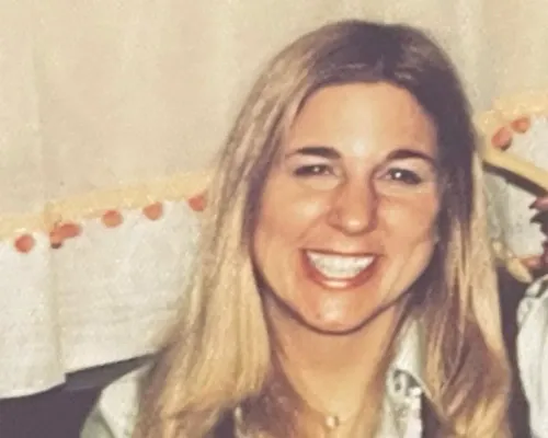 ابتسامة مارلا والدمان، ابنة الضحية باربرا والدمان، أثناء حديثها عن قضية والدتها التي قُتلت عام 1974. تظهر في الصورة بملابس عصرية وشعر طويل.