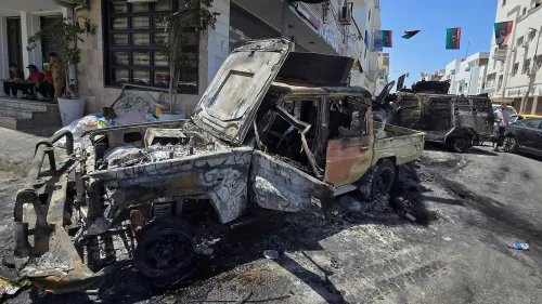سيارة محترقة في أحد شوارع طرابلس بعد اشتباكات عنيفة بين الميليشيات، تعكس تصاعد العنف في العاصمة الليبية.