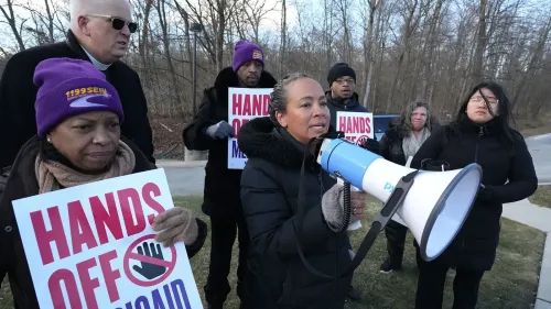 محتجون يحملون لافتات تطالب بحماية برنامج Medicaid، مع امرأة تتحدث عبر ميكروفون، في إطار جهود الدفاع عن الرعاية الصحية.