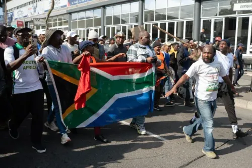 مظاهرة في Mossel Bay، حيث يحمل المشاركون علم جنوب أفريقيا، تعبيرًا عن الاحتجاجات ضد الهجرة والعنف الموجه ضد المهاجرين.