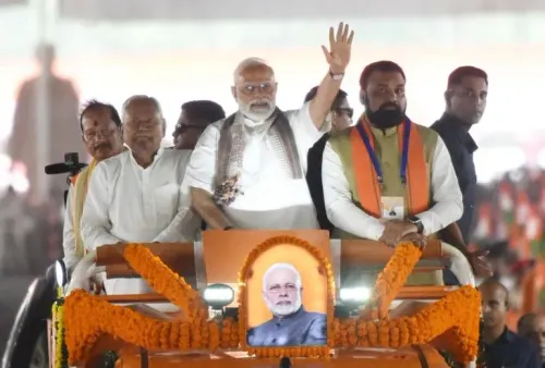 رئيس الوزراء الهندي ناريندرا مودي يلوح بيده خلال تجمع انتخابي في كيشانغانج، مع صورة له على المنصة، وسط حشود من المؤيدين.