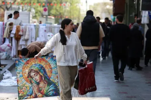 امرأة تحمل لوحة زجاجية ملونة تصور السيدة العذراء، تسير في شارع مزدحم في طهران، بينما يتجول الناس في الخلفية.