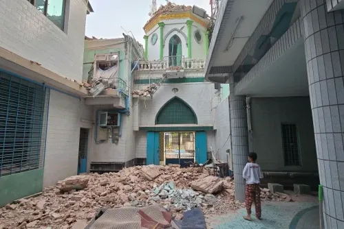 تظهر الصورة آثار الزلزال المدمر في ميانمار، مع أنقاض مبنى ومشاهد دمار واضح، بينما يقف طفل يتأمل الوضع.