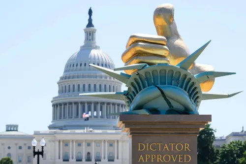 تمثال يجسد "الموافقة على الديكتاتور" مع تمثال الحرية في المقدمة ومبنى الكابيتول الأمريكي في الخلفية، يعكس جدل حرية التعبير.