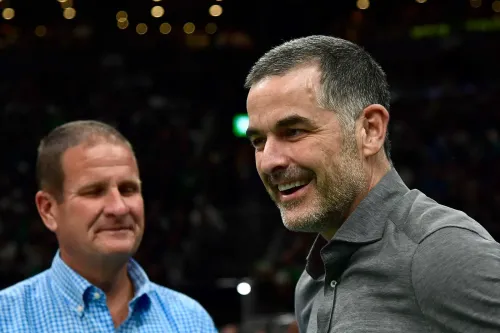 بيل تشيشولم مبتسم خلال حدث متعلق بفريق بوسطن سيلتيكس، مع وجود شخص آخر في الخلفية. يتناول الاجتماع تفاصيل صفقة شراء النادي.