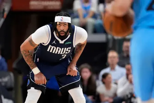 لاعب دالاس مافريكس يرتدي زي الفريق، يستعد للدفاع خلال مباراة حاسمة في الدوري الأمريكي للمحترفين، مع وجود جمهور في الخلفية.