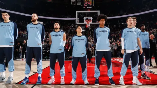 يوكي كاوامورا، أقصر لاعب في دوري الـ NBA، يقف مع زملائه في فريق ممفيس جريزليز قبل المباراة، مع التركيز على روح الفريق والتعاون.