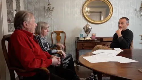 نيد جونسون وزوجته باميلا يجلسان مع صحفي، يتحدثون عن تجربتهما مع إدارة الضمان الاجتماعي بعد إعلان وفاته المزعومة.