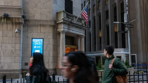 مدخل بورصة نيويورك مع لافتة إعلانات، حيث يمر الناس في الشارع، مما يعكس النشاط الاقتصادي والتجاري في المدينة.