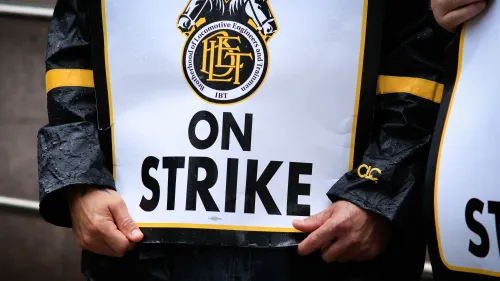 شخص يحمل لافتة مكتوب عليها "في إضراب" خلال احتجاج لمهندسي القطارات في نيوجيرسي، مع التركيز على مطالب زيادة الأجور.