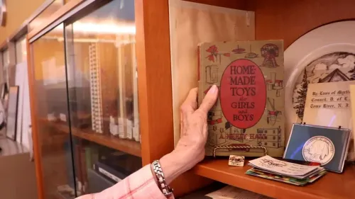 كتاب "ألعاب منزلية الصنع للفتيات والفتيان" يعود إلى عام 1911، ويظهر في المكتبة مع يد امرأة مسنّة تلامسه.