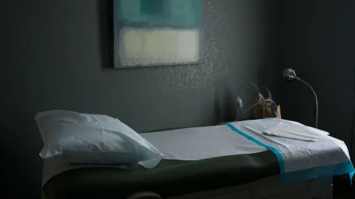 غرفة فحص طبية تحتوي على سرير مغطى بأغطية نظيفة، مع أدوات طبية وأضواء، تعكس بيئة تقديم خدمات الإجهاض في الولايات المتحدة.