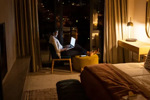 شخص يجلس في غرفة مضاءة بشكل خافت، يعمل على جهاز كمبيوتر محمول، مما يعكس نمط حياة البوم الليلي وتأثيره على صحة القلب.