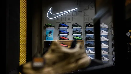 واجهة متجر نايكي تعرض مجموعة متنوعة من الأحذية الرياضية، مع شعار نايكي مضيء، تعكس عودة الشركة إلى أمازون واستراتيجياتها الجديدة في السوق.
