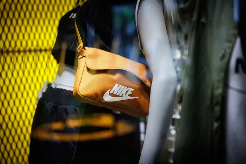 حقيبة برتقالية تحمل شعار نايكي، تظهر في واجهة متجر، تعكس جهود الشركة في إعادة التركيز على الملابس الرياضية الأساسية.