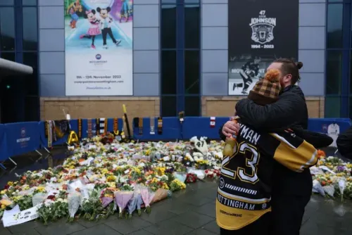 تظهر الصورة مشجعين يحتضنان أمام نصب تذكاري مغطى بالزهور لآدم جونسون، لاعب هوكي الجليد، بعد وفاته في حادث مؤسف.