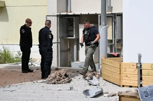 رجال الشرطة يتفقدون موقعًا تضرر من ضربة صاروخية في إسرائيل، مع وجود آثار دمار واضحة حولهم، مما يعكس تصاعد التوترات العسكرية.