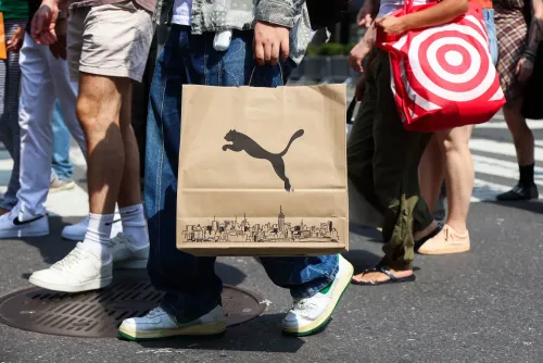 أحد المتسوقين يحمل حقيبة تسوق تحمل شعار شركة "Puma" بينما يسير في شارع مزدحم، مما يعكس نشاط الإنفاق الاستهلاكي في الاقتصاد الأمريكي.