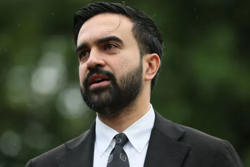 شخص يتحدث في مؤتمر صحفي، مع خلفية طبيعية، يعبر عن موقفه من الانتخابات والمنافسة السياسية في نيويورك.