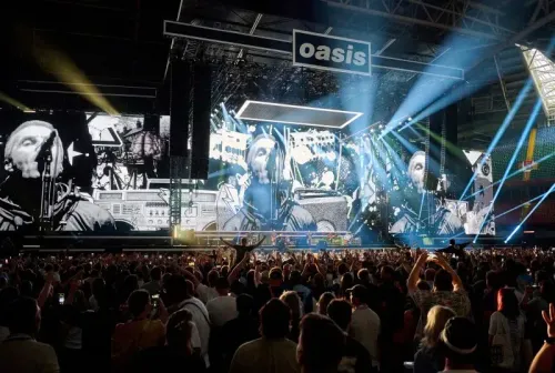 فرقة Oasis تؤدي في كارديف أمام جمهور حماسي، مع عرض بصري مذهل وأضواء ساطعة، مسترجعة أغانيها الشهيرة من التسعينيات.
