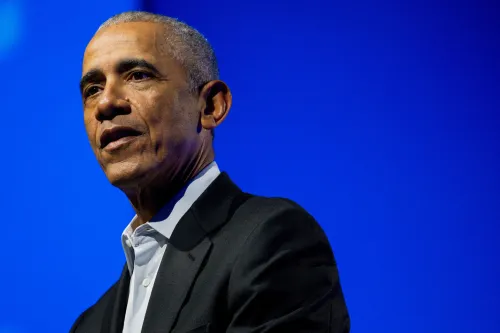 باراك أوباما يتحدث في حدث، مع خلفية زرقاء، معبرًا عن آرائه حول السياسة الأمريكية وتحديات الديمقراطية.