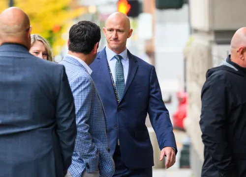 رجل يرتدي بدلة رسمية يسير مع مجموعة من الأشخاص خارج المحكمة، بعد جلسة استماع تتعلق بقضية طيار سابق في ألاسكا إيرلاينز.