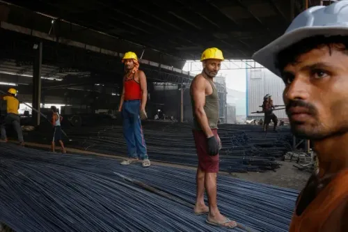 عمال في مصنع للصلب يرتدون خوذًا صفراء، يعملون على ترتيب قضبان الحديد في بيئة صناعية مزدحمة، تعكس تحديات العمل القاسي.