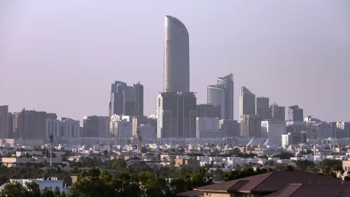 أفق مدينة أبوظبي يظهر فيه ناطحات السحاب الحديثة، مع التركيز على برج مميز، مما يعكس تطور البنية التحتية للذكاء الاصطناعي في الإمارات.