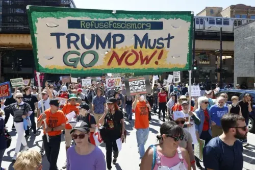 مظاهرة حاشدة في شيكاغو، حيث يحمل المتظاهرون لافتة تطالب برحيل ترامب، مع شعارات تدعو لمقاومة الفساد وحماية حقوق العمال.