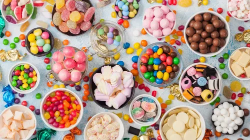 تشكيلة ملونة من الحلويات والأطعمة المزينة بأصباغ صناعية، تعكس القلق حول تأثيرها على صحة الأطفال وسلوكهم.