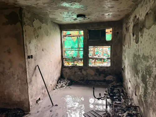 غرفة متضررة بشدة من حريق في مجمع سكني بهونغ كونغ، تظهر جدران متفحمة ونوافذ محطمة، تعكس آثار الكارثة المأساوية.