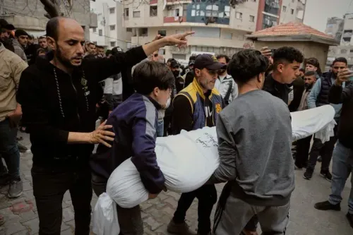 مواطنون يحملون جثمانًا مغطى في شوارع غزة، وسط حشود من الناس، في ظل تصاعد العنف والضغوط الإنسانية في المنطقة.