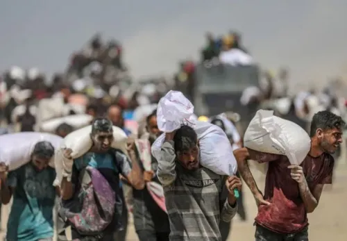 رجال يحملون أكياس مساعدات غذائية في غزة، وسط تجمع كبير للناس، في ظل أزمة إنسانية متفاقمة بسبب الحصار والعمليات العسكرية.