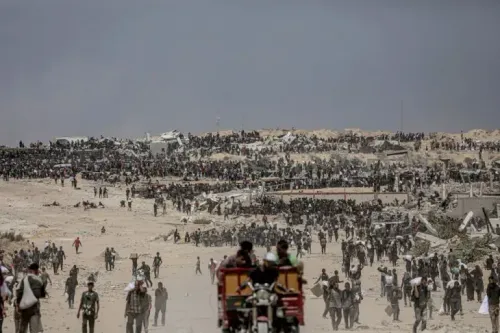 تجمع حشود من الفلسطينيين في منطقة دير البلح بغزة، بحثًا عن المساعدات الإنسانية وسط الدمار الناتج عن القصف الإسرائيلي.