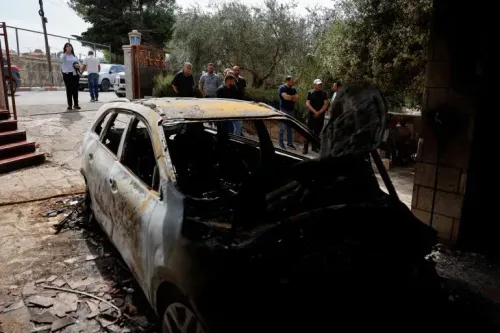 سيارة محترقة في بلدة سلواد بعد هجوم مستوطنين إسرائيليين، مع تجمع السكان المحليين لمشاهدة الأضرار.