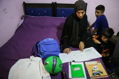 امرأة فلسطينية ترتدي الحجاب تجلس على سرير أرجواني مع طفلين، محاطة بكتب مدرسية، حقيبة ظهر، وكرة قدم، في مشهد يعكس حياة الأطفال في ظل النزاع.