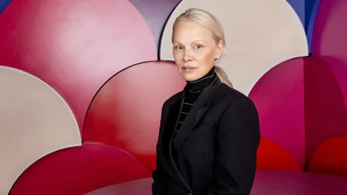 باميلا أندرسون ترتدي ملابس سوداء، جالسة أمام خلفية ملونة تتكون من دوائر حمراء ووردية، تعكس أجواء فيلمها "فتاة الاستعراض الأخيرة".