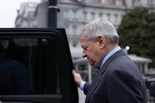 رجل يرتدي بدلة رسمية يغادر سيارة، يبدو عليه القلق، في خلفية مشهد حضري يعكس أجواء البيت الأبيض.