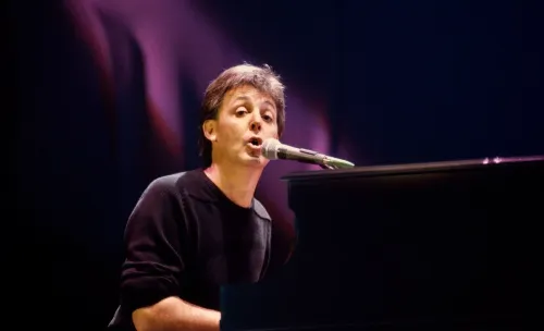 بول مكارتني يغني "Let It Be" على البيانو في حفل Live Aid عام 1985، وسط أضواء المسرح والجمهور.