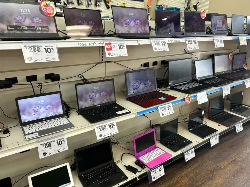 أجهزة كمبيوتر محمولة معروضة على رف في متجر رهن، مع ملصقات أسعار توضح التخفيضات، تعكس خيارات التسوق الاقتصادية لموسم العودة إلى المدرسة.