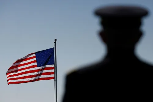 علم أمريكي يرفرف في الخلفية مع ظل شخص يرتدي زيًا عسكريًا، مما يعكس القضايا المتعلقة بالأمن القومي ومتلازمة هافانا.