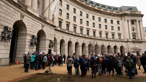 تجمع حشد كبير أمام مبنى وكالة حماية البيئة في واشنطن، مع لافتات تعبر عن القلق من تجميد التمويل الفيدرالي.