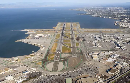 مطار سان فرانسيسكو الدولي يظهر من الجو، مع مدرجات الطائرات والمرافق المحيطة، في سياق اعتقال طيار بتهم خطيرة.