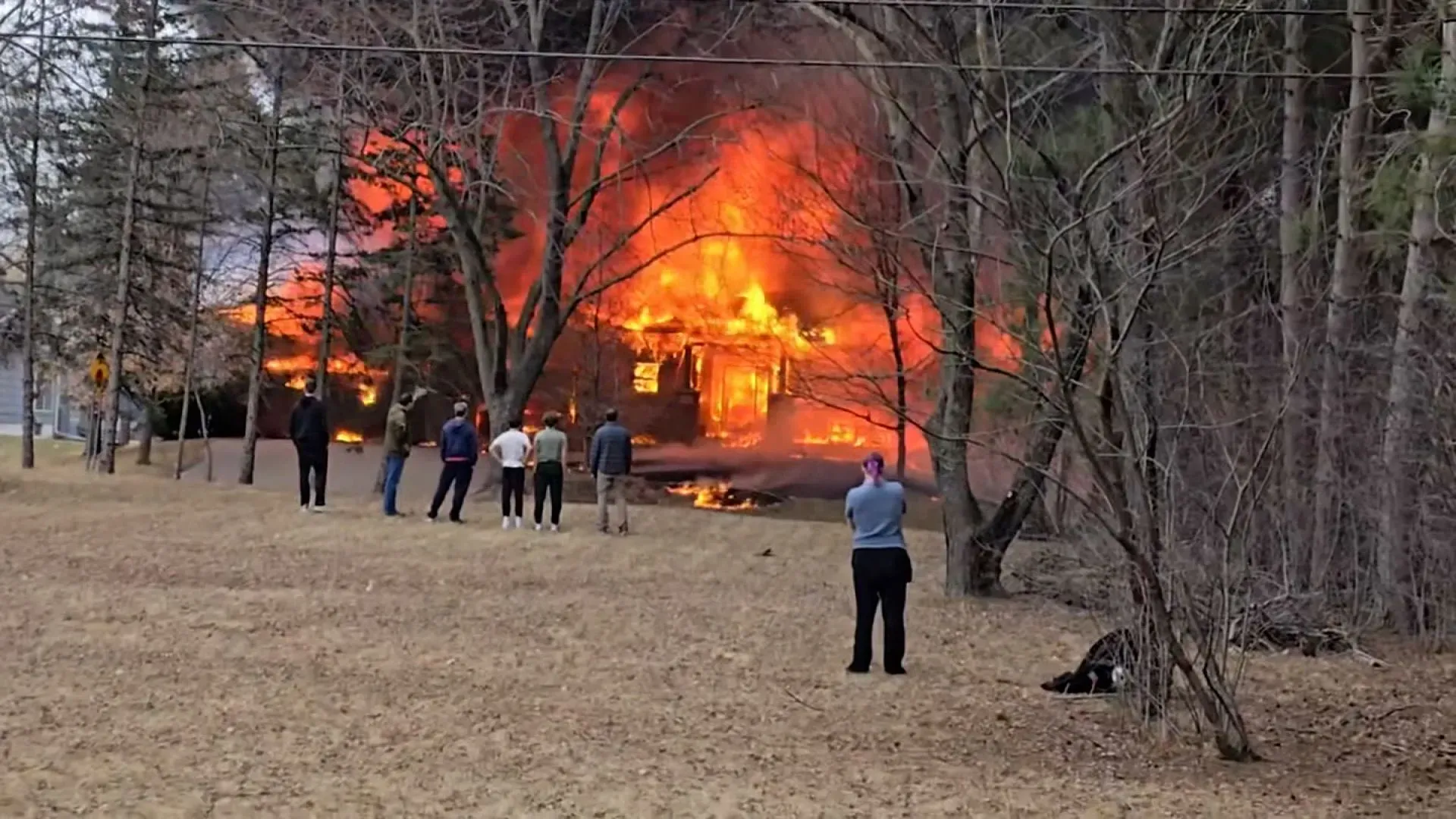 منزل في بروكلين بارك بولاية مينيسوتا يشتعل فيه النيران بعد اصطدام طائرة صغيرة به، مع تجمع الناس في المنطقة لمشاهدة الحادث.